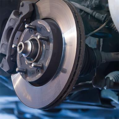Close-up of a cars front wheel brake assembly. The image shows a metallic brake disc and caliper, with visible bolts and screws. The shiny metal surface contrasts with the darker surrounding components, highlighting the brake system—just what youd expect from a top mechanic near me.