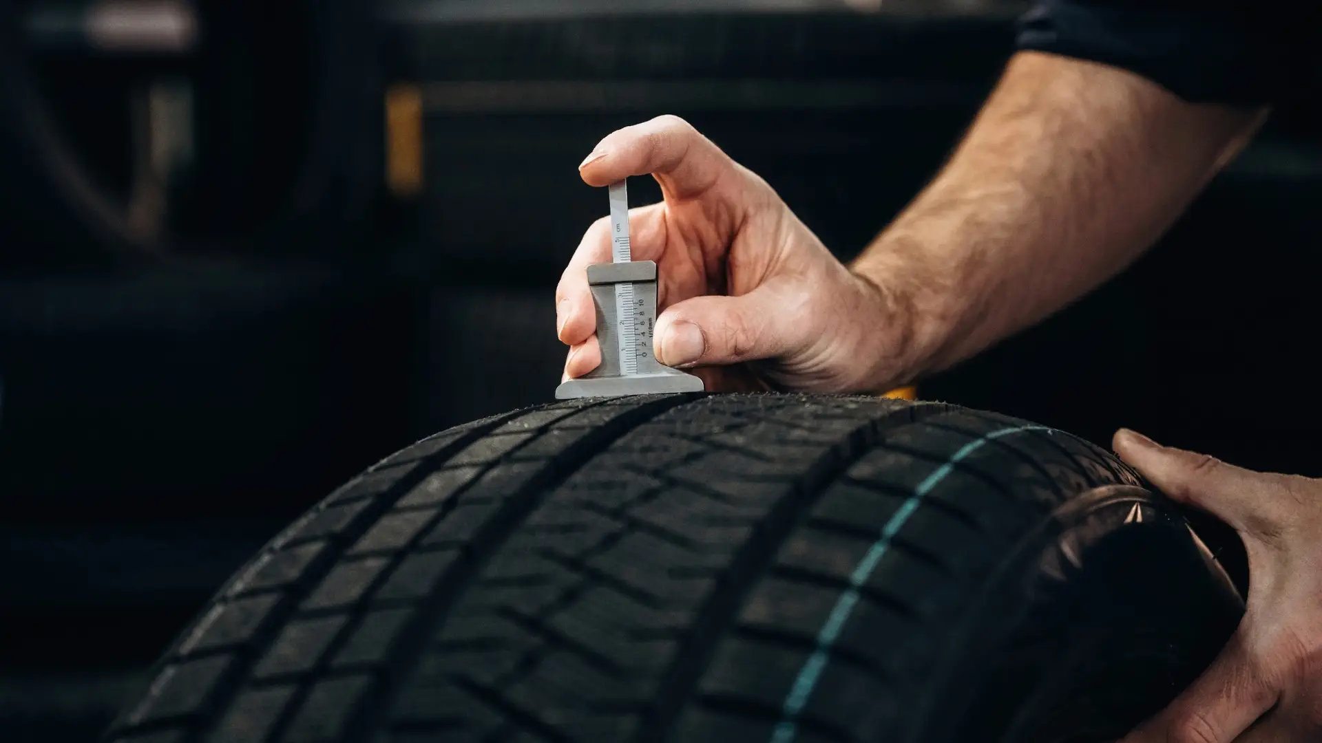 Technician checking tread depth to decide whether to replace two winter tires or all four