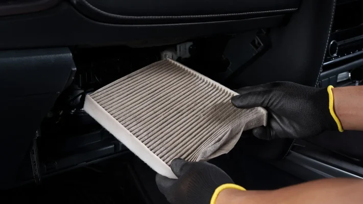 Technician checking a cabin air filter for wildfire smoke and summer debris