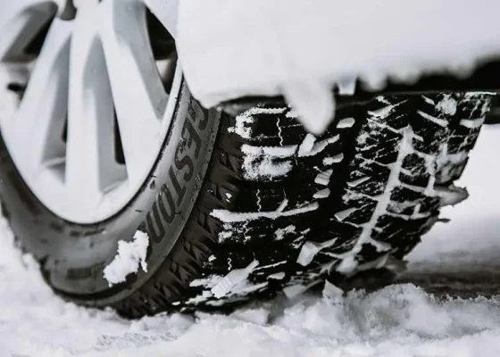 The Mufflerman Close-up of a car tire on a snowy surface, with snow clinging to its treads—an ideal scene for showcasing the Ontario Winter Tire Insurance Discount. The wheel is partially visible, and compacted snow emphasizes the need for reliable winter tires.