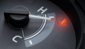 The Mufflerman, Mechanic Near Me Close-up of a car’s temperature gauge with a needle pointing to “H” for hot. A red warning light features a thermometer icon, signaling the need for Engine Cooling System service as the radiator struggles to prevent overheating.